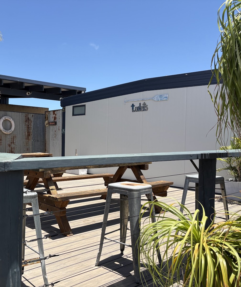 The outdoor deck with high stools and timber picnic tables in the sun