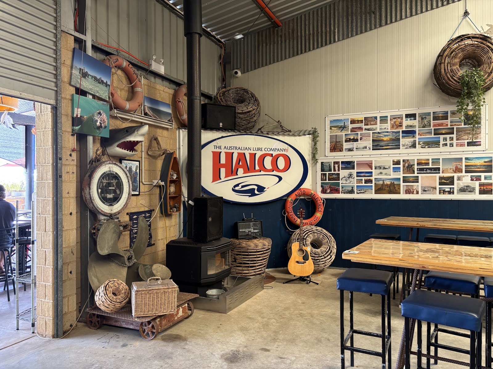 A corner of the shed with a wood heater, rope, cray pots and a wall of photos